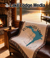 Throw blanket with Rushford Lake map and compass design on a leather couch.