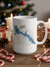 White mug with Bass Lake California map and compass graphic, surrounded by Christmas decorations.