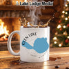 White mug with Glen Lake Michigan map and compass design, in a cozy setting.