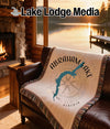 Woven blanket with Abraham Lake, Alberta map design on a leather couch.