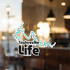 Taylorsville Life sticker with blue lake outline on glass, blurred background.