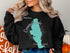 Black sweatshirt with a teal compass and "Beautiful Conneaut Lake Pennsylvania" graphic.