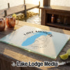 A glass cutting board featuring a blue map of Lake Michigan and compass design on a wooden outdoor bar.