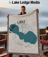 Man holds woven throw featuring teal Pearl Lake map and compass graphic.