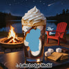 Glass with soft serve and coffee in front of campfire and lake at night.