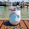 A white travel tumbler featuring a Floyd Lake, Minnesota map graphic, sitting on a wooden boat deck with a lake scene in the background.