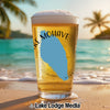 Beer glass with "Lake Mohave" text and blue Nevada shape on beach background.