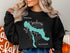 Black sweatshirt with a blue outline map of Lake Charlevoix and compass rose.