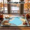 A custom glass cutting board featuring a map of Emerald Lake, Canada, surrounded by crackers, cheese, and pecans.