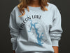 Light blue sweatshirt with Falcon Lake Texas map and compass graphic.