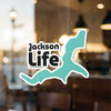 Jackson Life sticker with a teal abstract shape on a glass surface.