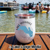 A white insulated wine tumbler featuring a Lake Wawasee, Indiana design sits on a wooden dock with people swimming in the lake behind it.