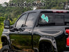 Turquoise Almanor Life decal on a black truck window over trees.