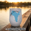 A white insulated wine tumbler featuring a blue map of Lake Stevens, Washington, rests on a wooden dock at sunset.