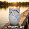 A white stemless tumbler with Lake Panorama Iowa graphics rests on a wooden dock at sunset.