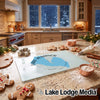 A glass cutting board featuring a blue Lake Almanor map design rests on a granite kitchen counter surrounded by holiday baking supplies.
