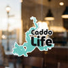 Teal outline sticker with "Caddo Life" text on glass surface.