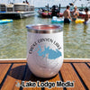 A white insulated tumbler with a Choke Canyon Lake graphic rests on a wooden boat deck.