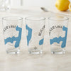 Three clear glasses with blue Augur Lake map graphics and compass rose designs.