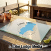 A glass cutting board featuring a blue map of Lake Piru, California, rests on an outdoor wooden table.