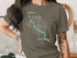Woman wearing a brown t-shirt with a Lake Chelan compass design.