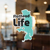 Flathead Life sticker with teal lake shape on a window