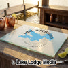 A glass cutting board featuring a blue map of Lake Arrowhead rests on a wooden table.