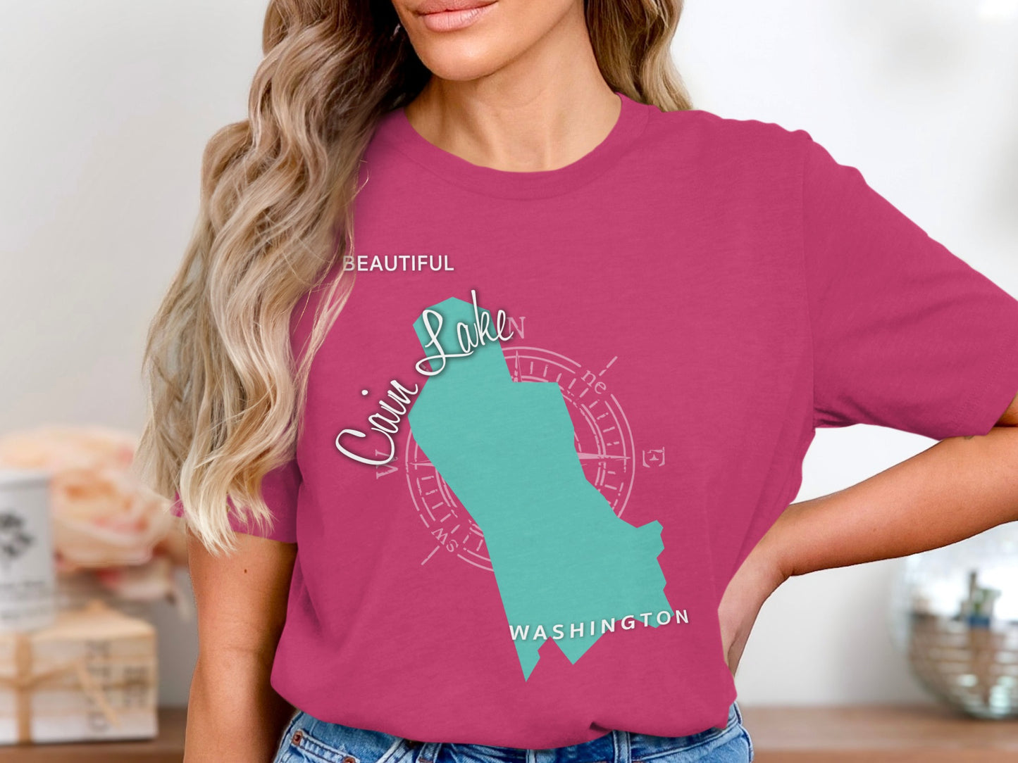 Teal outline map of Lake, Washington with compass rose on pink t-shirt.