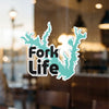 Teal map outline sticker with black text "Fork Life" on glass.