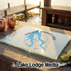 A custom glass cutting board with a blue Willow Springs Lake map design resting on an outdoor wooden bar.