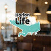 Harlan Life text over a teal outline of a body of water on a window.