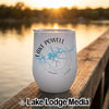 A white tumbler featuring a blue map of Lake Powell, a compass graphic, and text reading Lake Powell, Utah, resting on a wooden dock at sunset.