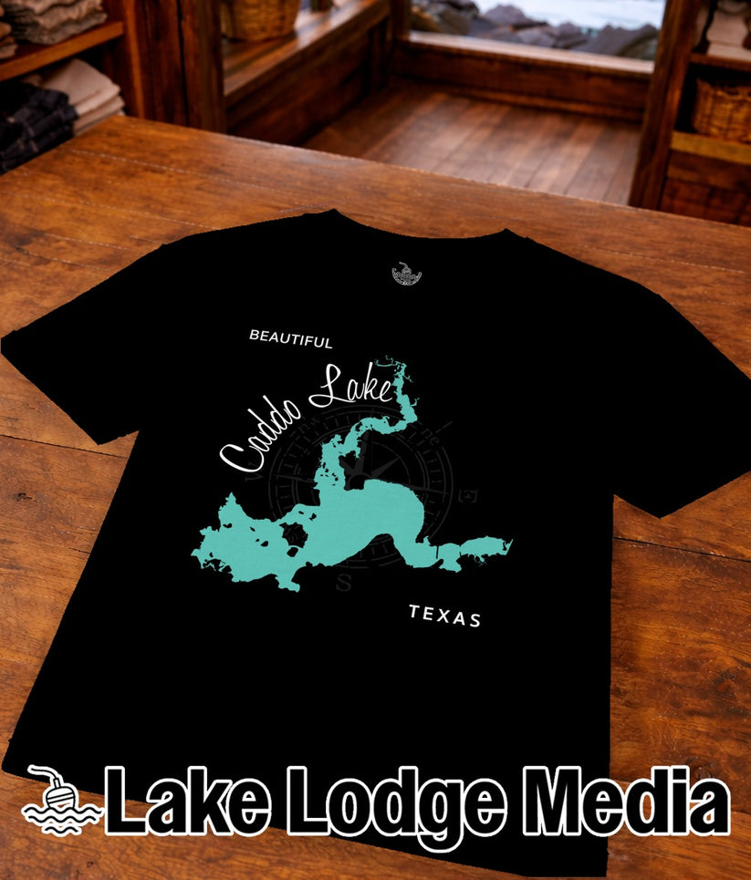 Black t-shirt with a teal outline map of Caddo Lake and "Lake Lodge Media" text.