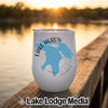 White tumbler with a blue map of Lake Huron and compass design, sitting on a wooden dock at sunset.