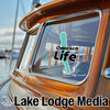 Wood boat detail with "OWASCO Life" sticker and "Lake Lodge Media" text.