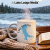 White mug with "Lake Quivira Kansas" design on a wooden table with a book and blanket.