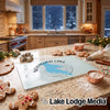 A glass cutting board printed with a map of Newfound Lake sits on a granite kitchen counter surrounded by baking supplies.