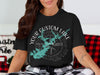 Black t-shirt with a compass rose, turquoise lake outline, and text "YOUR CUSTOM LAKE".