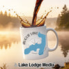 White mug with Augur Lake, New York design, with coffee pouring into it.