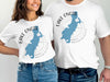 White t-shirts featuring a blue map of Lake Onota, Massachusetts, and compass graphic.