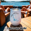 A white tumbler with Lake Oroville graphics rests on a wooden boat table with two women relaxing in the background.