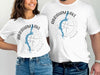 White t-shirts featuring "Abraham Lake Alberta" map graphic with compass Rose.