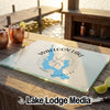 A glass cutting board featuring a blue map of Walloon Lake, Michigan, rests on a wooden outdoor bar.