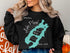 Black sweatshirt with a turquoise Lake Placid, New York map and compass graphic.