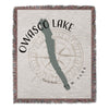 Woven throw blanket with Owasco Lake outline, compass, and New York text.