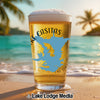 Glass of beer with "Lake Casitas" label on a beach with palm trees.