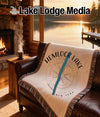 Hemlock Lake woven blanket with compass design on leather sofa near fireplace.