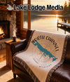 Tapestry blanket with "North Channel Michigan" map design on a leather couch.