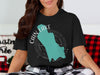 Black t-shirt featuring a teal outline of Washington with text "Cain Lake" and a compass rose.