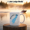 White mug with "Moraine Lake Alberta" design on a lake at sunrise.